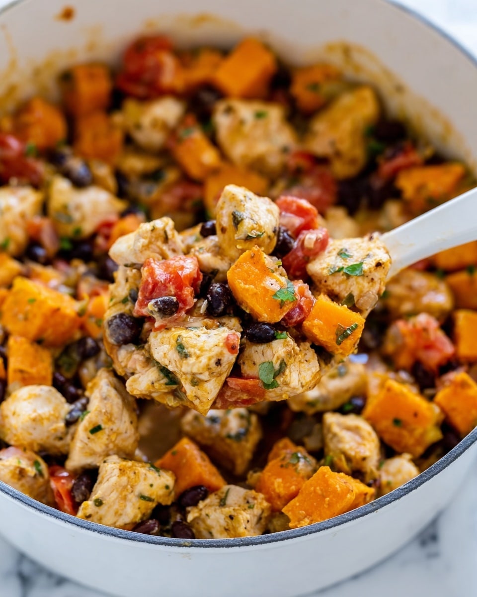 The image shows a white plate holding a colorful mixed dish made of many layers. The bottom layer is mostly melted yellow cheese that looks soft and sticky. On top of that, there are many dark black beans spread all over with some soft cooked light orange sweet potato chunks mixed in. There are also pieces of cooked red tomatoes and light yellow onions visible among the beans and sweet potatoes. The dish looks sprinkled with green dried herbs, adding texture and color. In the background, there is a white pan slightly out of focus with more of the same food inside. The plate is on a white marbled surface. photo taken with an iphone --ar 4:5 --v 7