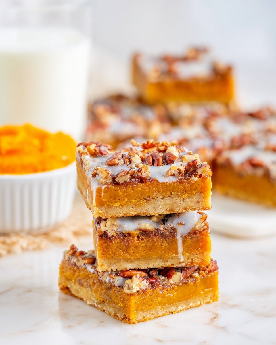 The image shows several square pecan dessert bars stacked and arranged on a white marbled surface. Each bar has three clear layers: the bottom crust is light golden brown and crumbly, the middle layer is a rich orange filling, and the top layer is a mix of glossy pecan halves covered with a shiny, slightly melted, creamy glaze. In the background, a white ramekin filled with orange pumpkin puree and a glass of milk are partially visible, softly blurred. The whole scene is bright and inviting, highlighting the warm colors and textures of the pecan bars. photo taken with an iphone --ar 4:5 --v 7