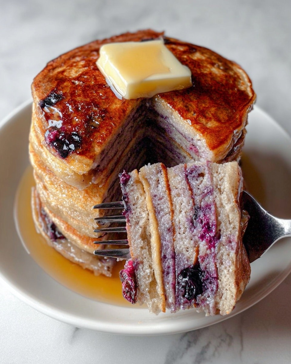 A stack of six thick, round pancakes with a golden-brown top layer sits on a white plate over a white marbled surface. The pancakes have a light purple interior, showing specks of darker purple and whole blueberries inside. A slice of pale yellow butter melts on the top pancake, and a shiny drizzle of syrup covers part of the stack. A black fork held by a woman's hand lifts a piece of the pancakes, revealing the layers and berries clearly. Photo taken with an iphone --ar 4:5 --v 7
