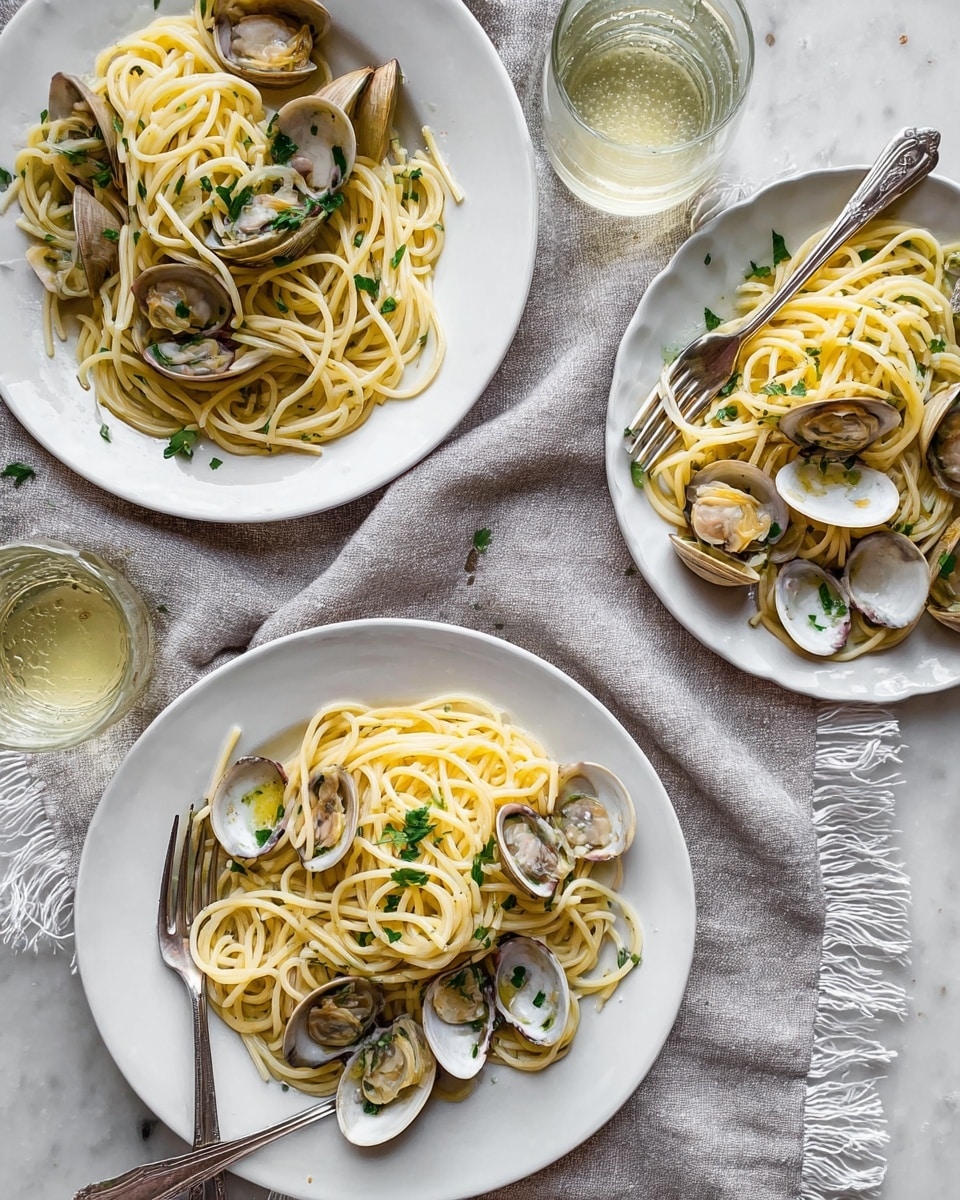The image shows three white plates filled with spaghetti and clams, each with a fork resting on the edge. The spaghetti is pale yellow with a smooth and slightly glossy texture, intertwined with opened clam shells that are white and light brown inside. Small green parsley leaves are sprinkled on top of each plate, adding contrast. The plates sit on a soft gray fabric with fringed edges, placed over a white marbled surface. Two clear glasses with a light yellow drink are also visible, adding balance to the composition. photo taken with an iphone --ar 4:5 --v 7