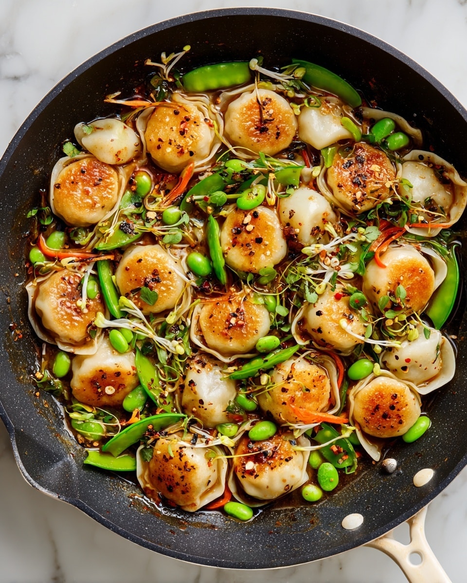 A close-up top view of a black cooking pan with a white handle filled with pan-fried dumplings, each golden brown and slightly crispy on the edges, mixed with bright green snow peas, green edamame beans, thin orange carrot sticks, thin white bean sprouts, and round white rice cakes, all coated in a glossy brown sauce with visible black pepper flakes. The pan sits on a white marbled surface. Photo taken with an iphone --ar 4:5 --v 7