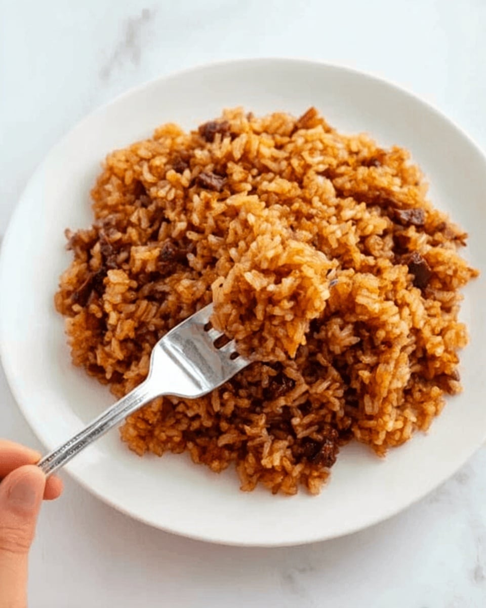 A close-up view of crispy cooked rice with a mix of deep golden brown and darker brown bits layered throughout, giving a crunchy texture alongside softer, light golden rice grains. Small bright green pieces are scattered on the rice, adding a fresh pop of color, while a wooden spoon lifts a portion, showing the toasted layers clearly. The dish rests on a white marbled surface, enhancing the warm tones of the rice. Photo taken with an iphone --ar 4:5 --v 7