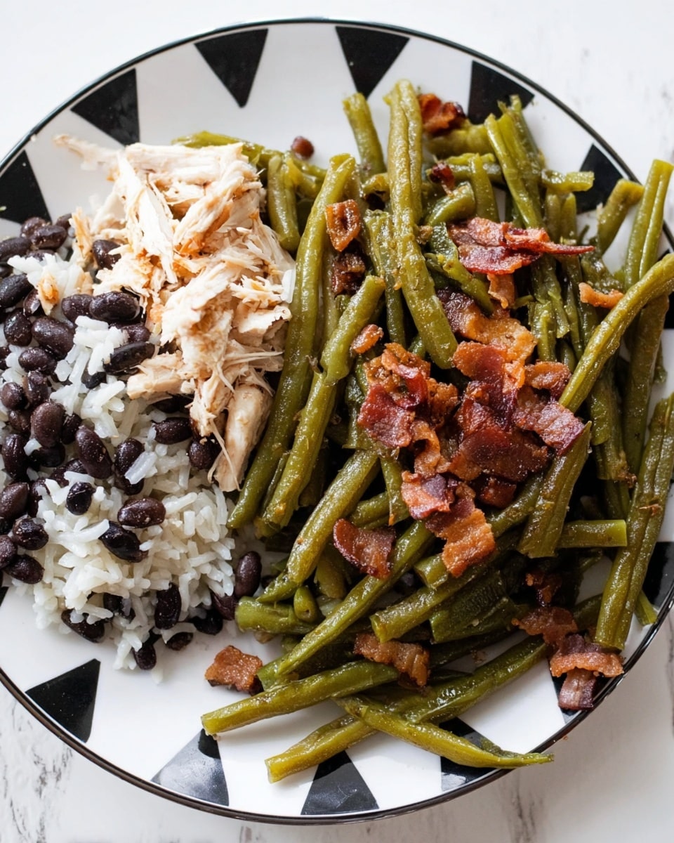 A white plate with black triangular details around the edge holds two main sections of food: on the left, a layer of white rice mixed with black beans topped with shredded cooked white chicken, showing a soft texture; on the right, a serving of green beans cooked with crispy brown bacon pieces scattered on top, the green beans look tender and slightly glossy. The plate is set on a white marbled surface. photo taken with an iphone --ar 4:5 --v 7