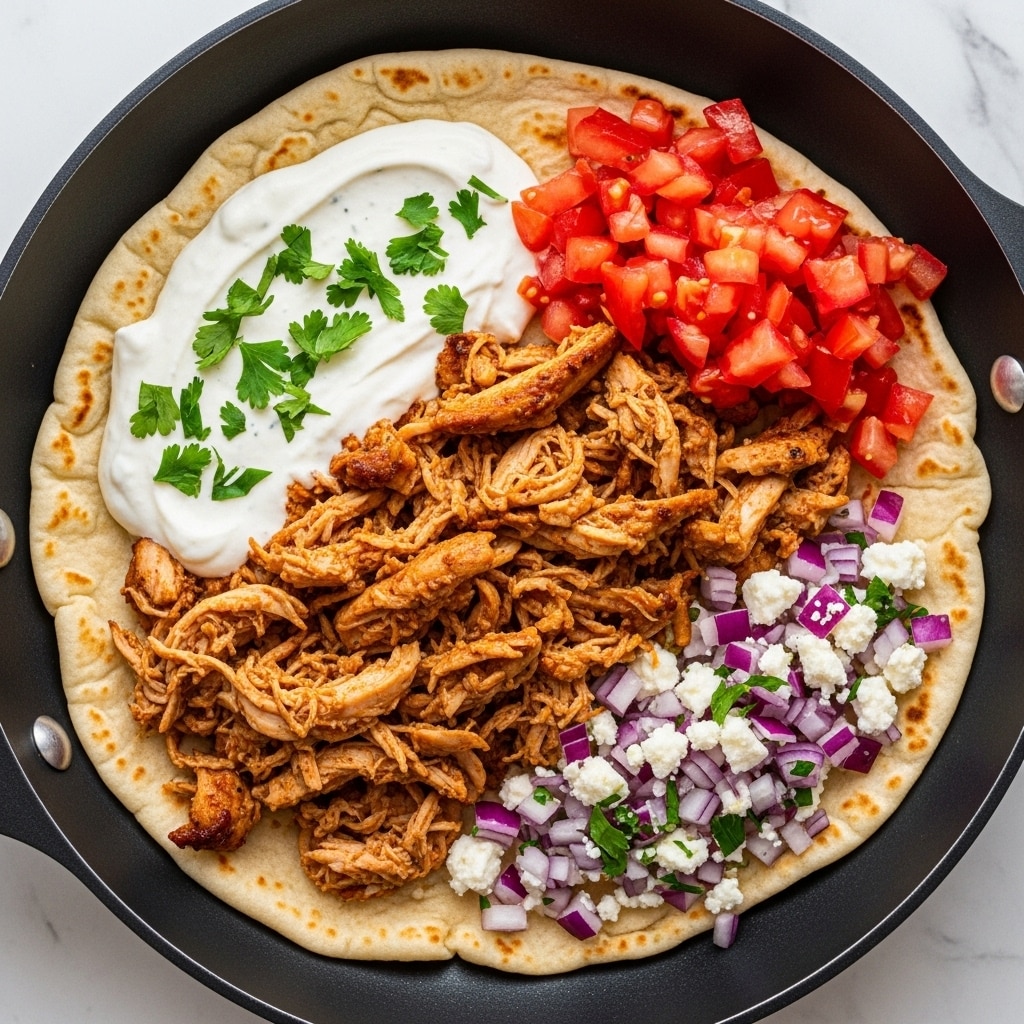 A black pan holds a layered dish starting with a soft, lightly toasted flatbread at the bottom. On top, tender shredded chicken with a brown, slightly charred texture is spread in the middle. To the top right side, there is a heap of bright red diced tomatoes, and at the bottom right, small chunks of purple onion mixed with crumbled white cheese and green herbs. On the left side, a creamy white sauce with a smooth texture is placed, sprinkled with chopped green herbs. The dish sits on a white marbled surface. Photo taken with an iphone --ar 4:5 --v 7