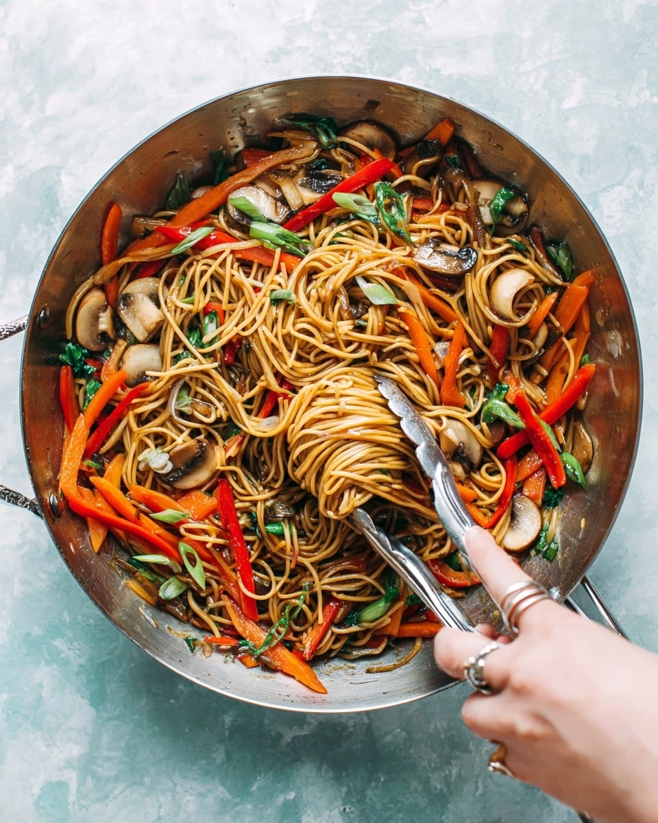 A shiny metal pan holds cooked noodles mixed with several colorful vegetables. The bottom layer is thin noodles in a light brown sauce, above which sit thin orange carrot sticks, sliced red bell peppers, and round beige mushroom slices. Scattered green onion rings and green leafy bits add fresh color on top. A woman's hand with silver rings is holding metal tongs that gently lift some noodles from the pan. The pan is placed on a white marbled textured surface. photo taken with an iphone --ar 4:5 --v 7