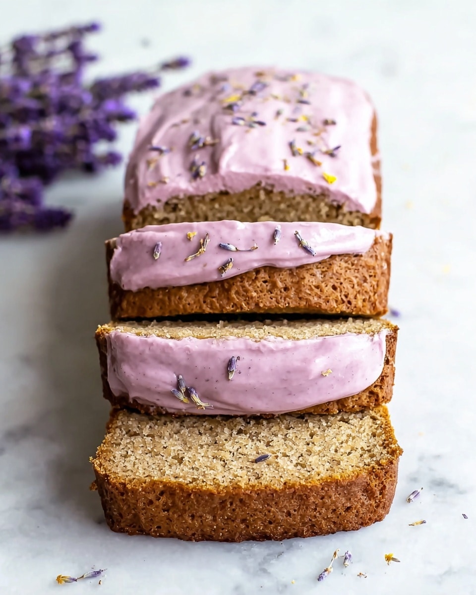 A loaf cake is shown with three thick slices cut from it, all stacked one on top of the other. The cake is brown with a coarse, slightly crumbly texture. A light purple-pink frosting with small specks is spread smoothly on the top of the loaf and between each slice, with bits of dried lavender sprinkled on top of the frosting. The background is a white marbled texture with a small bunch of purple lavender flowers on the left side. photo taken with an iphone --ar 4:5 --v 7