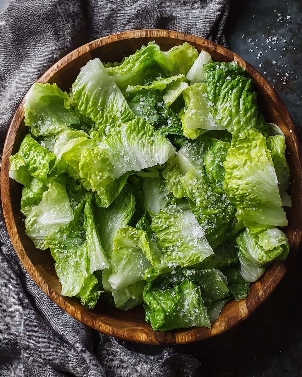 The image shows a white plate filled with a fresh salad of two main layers: the bottom layer has large, light green leafy lettuce, while the top layer has darker green leaves sprinkled with white grated cheese. There are small red chili flakes scattered lightly over the salad. A silver fork rests on the left side of the plate. The plate is set on a white marbled surface. photo taken with an iphone --ar 4:5 --v 7