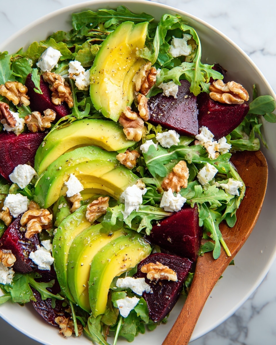 A white bowl filled with a fresh salad showing four main layers: at the bottom, dark green arugula leaves with a slightly rough texture; on top of that, wedges of bright yellow-green avocado with smooth skin and deep purple-red beet slices, cut thick and juicy; scattered over these are light brown, crunchy walnut pieces; and finally, small white crumbles of soft goat cheese spread evenly across the salad. The salad is lightly drizzled with dressing and a wooden spoon peeks from the right side. The background shows a white marbled texture. photo taken with an iphone --ar 4:5 --v 7